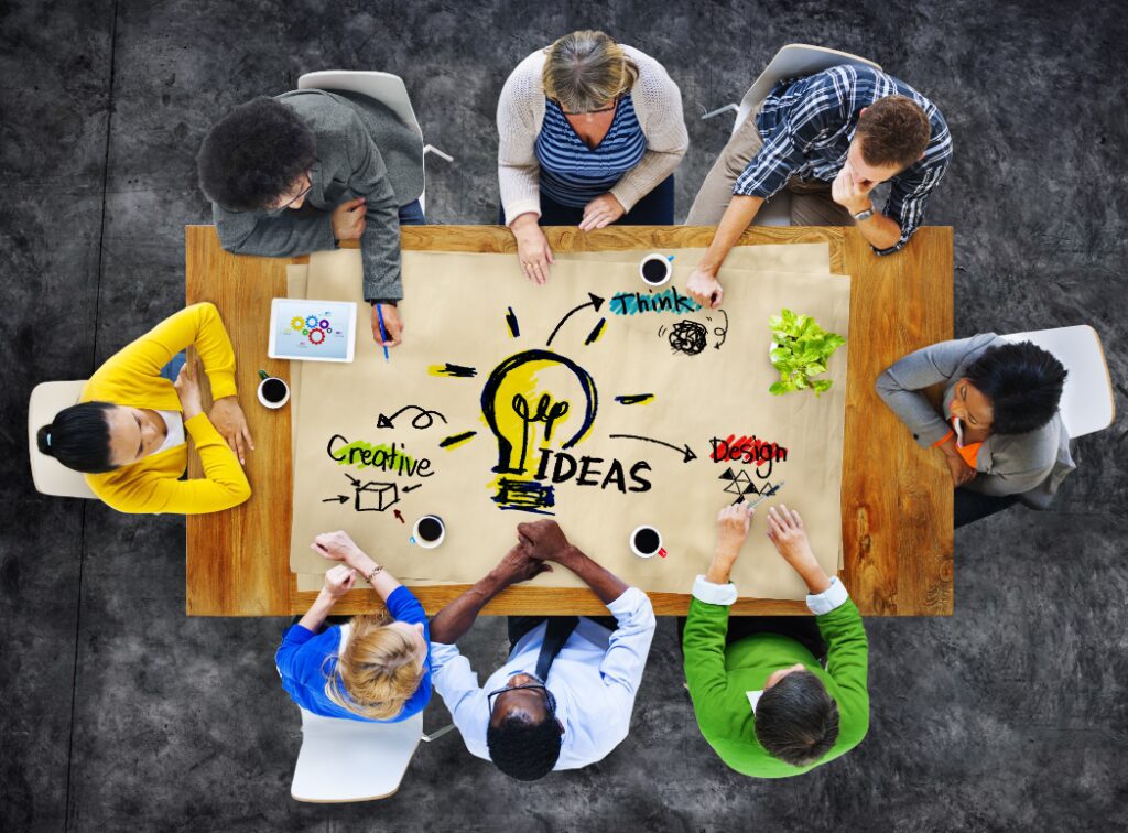 A diverse team brainstorming creative ideas around a table with drawings and notes.