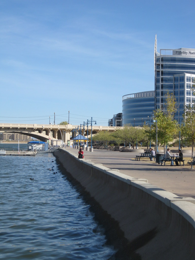 A city riverfront is seen with people chatting