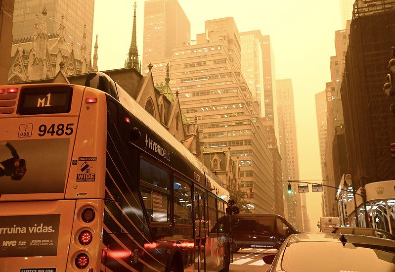 City street with bus and orange sky.