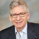 Smiling older man wearing glasses and suit